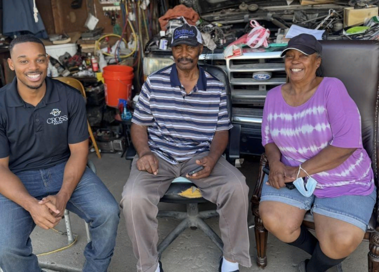 Cross Builds representative smiling with elderly Houston community residents in a garage setting